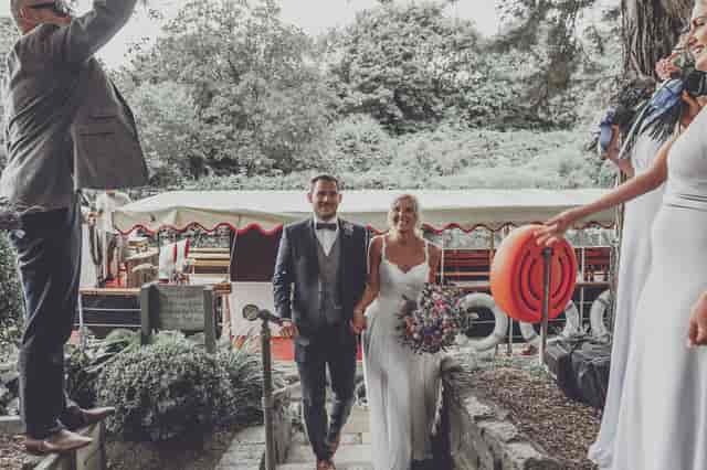 Joyful couple celebrating wedding at Beeses Riverside Bar with scenic outdoor backdrop.