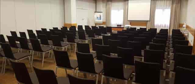 Victoria Suite meeting room at Novotel Bristol, featuring black chairs and a presentation screen.