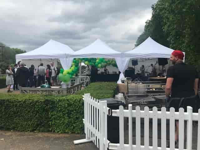 Vibrant outdoor event at Pavilion Gardens with white tents and green balloons.