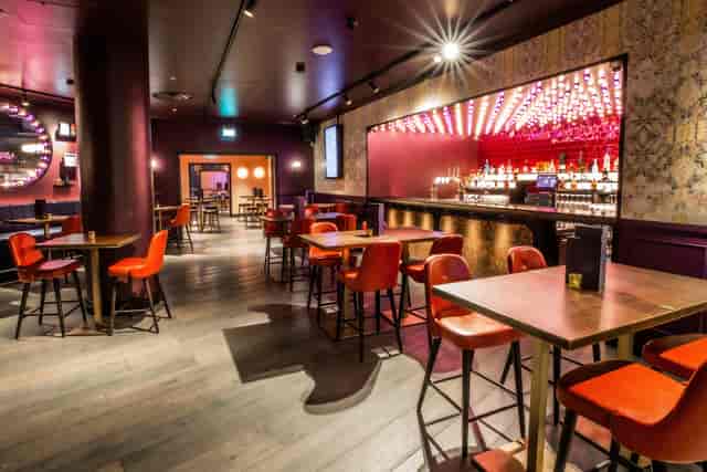 Christmas party at Puttshack Bank with vibrant red seating and modern decor.