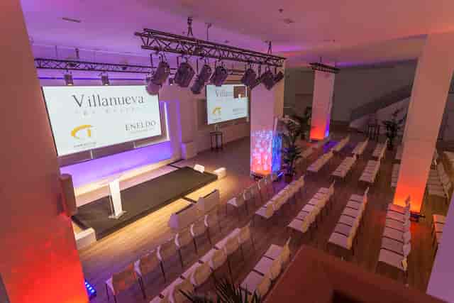 Modern conference space with rows of chairs and stage at ESPACIO VILLANUEVA.