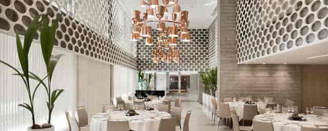 Modern meeting space with elegant tables and copper chandelier for upscale events.