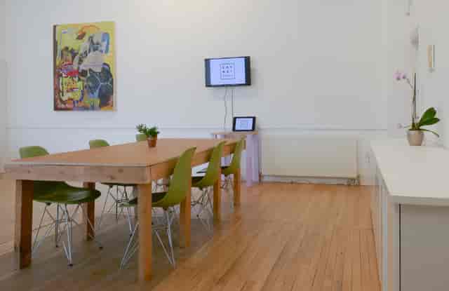 Modern meeting space with wooden table and green chairs, perfect for workshops and brainstorming.
