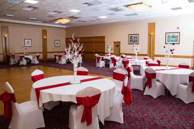 Castellan Suite at Britannia Hotel: elegant event space for weddings with round tables and red accents.