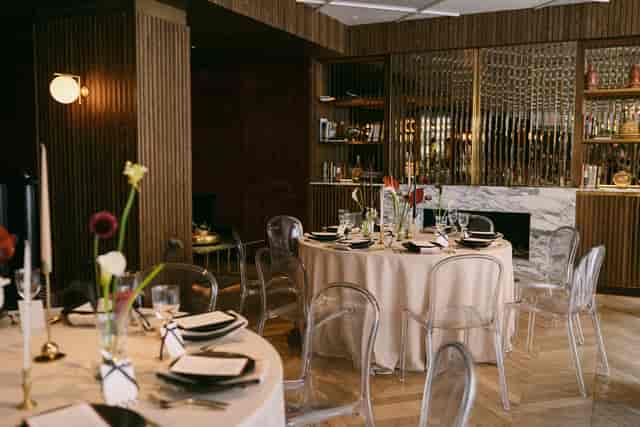 Elegant dining space at Number Six, featuring round tables and modern acrylic chairs for upscale events.