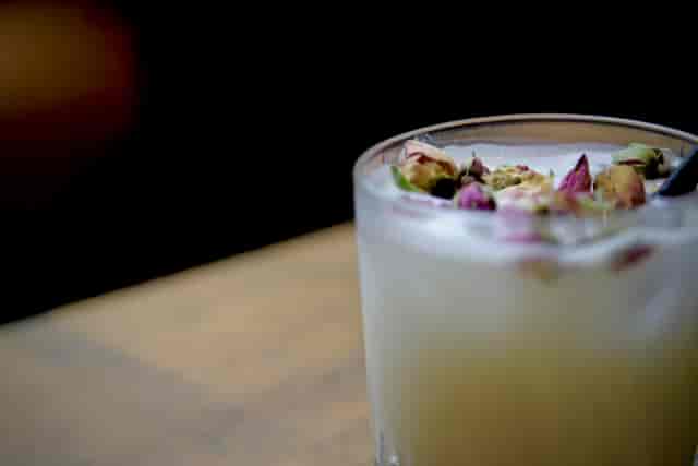Signature cocktail garnished with rose petals at OmStudio, perfect for events and meetings.