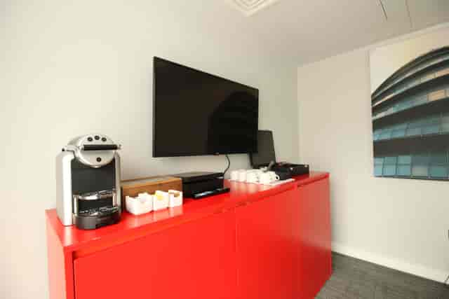 Modern meeting room at Hampton by Hilton London Docklands with coffee machine and TV.