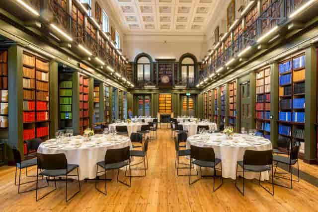 Elegant event space with round tables and bookshelves, perfect for formal gatherings.
