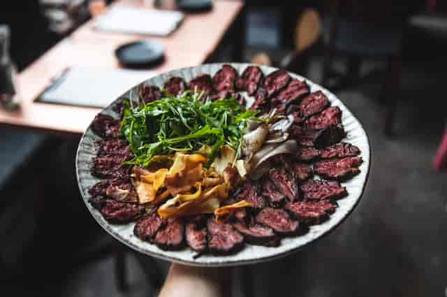 Sliced meat platter with greens and veggies at VAGABOND MONUMENT event catering.