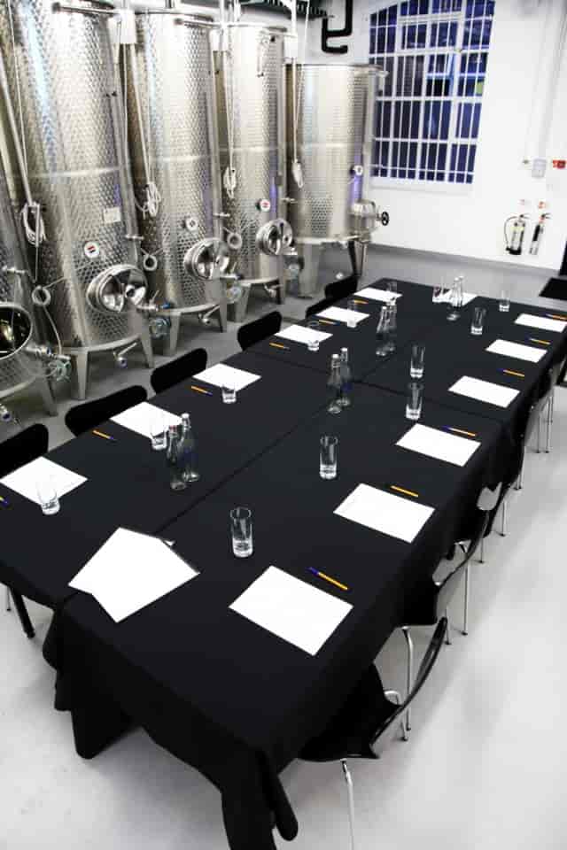 Tank Room at London Cru Winery: industrial meeting space with black table for corporate retreats.