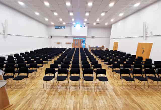 Main Hall in Queens Gate House set for a seminar with rows of black chairs.