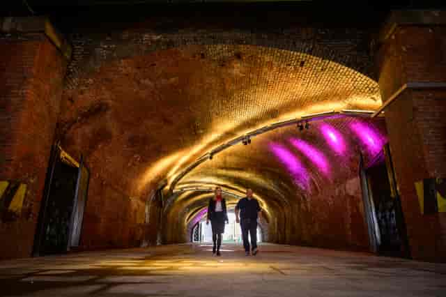 The Arch event space with arched brick tunnel and vibrant purple lighting for receptions.