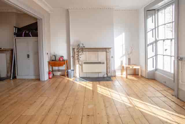 Spacious event space with wooden floors and fireplace, perfect for meetings and workshops.