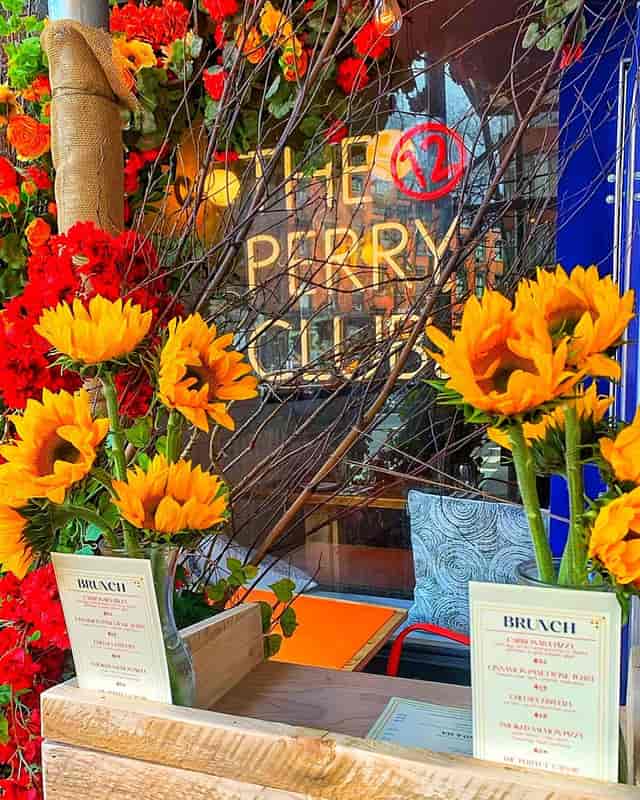 Sunflowers and red flowers frame the Perry Club window, ideal for events and gatherings.