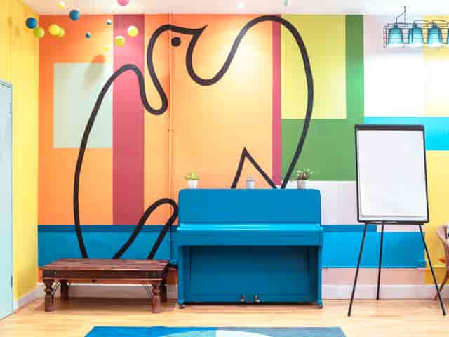 Vibrant Matisse London Art House breakout space with piano and whiteboard for creative workshops.