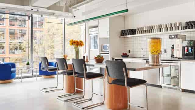 Modern kitchen at WeWork 1701, ideal for networking events with bar seating and sunflowers.