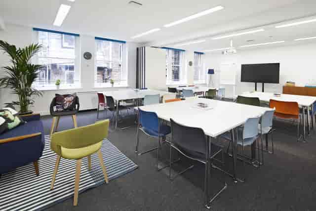 Modern meeting room with colorful chairs, ideal for workshops and team meetings.