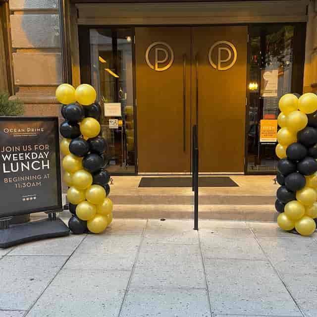 Elegant Arlington Room entrance with black and gold balloon arches for upscale lunch events.