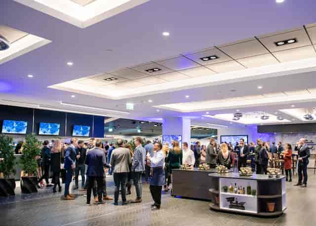 Networking event at Tottenham Hotspur Stadium with bright lighting and food stations.