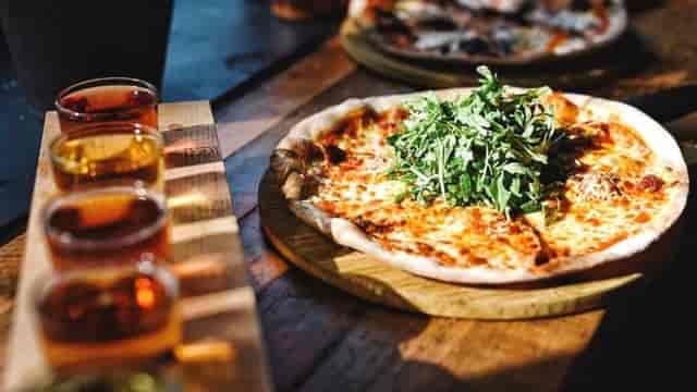 "Pizza with arugula and sauces at Cider Snug, perfect for events and networking."