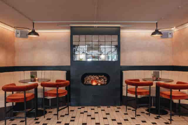 Stylish meeting space with plush orange chairs and chic fireplace for networking events.