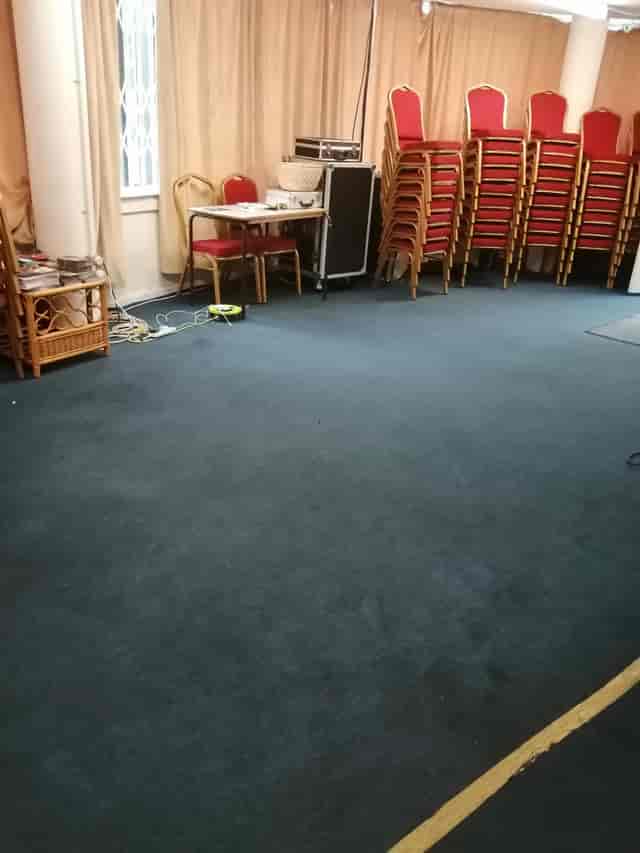 Meeting space in The Healing Centre with stacked chairs and AV cables for events.