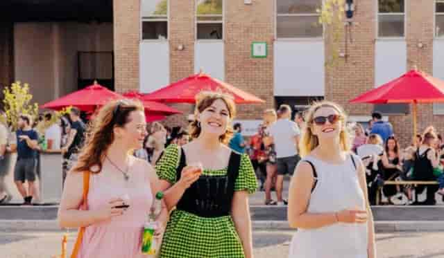 Outdoor event at Renegade Urban Winery with vibrant red umbrellas and smiling attendees.