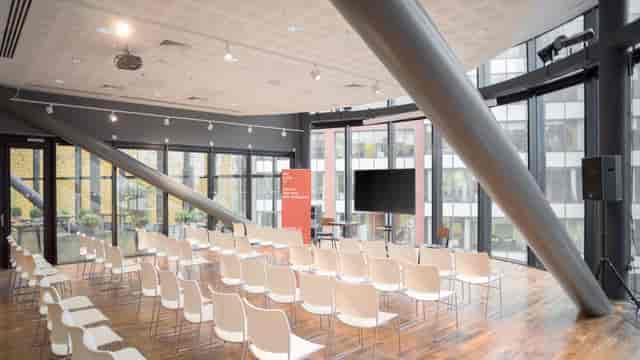 Modern event space with white chairs and natural light for workshops and seminars.