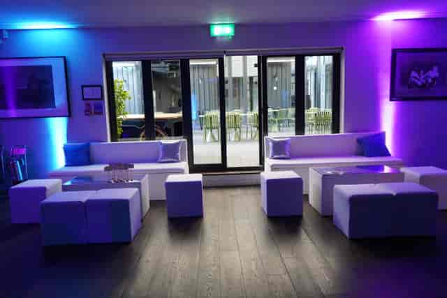 Modern event lounge with sleek white furniture and purple lighting for networking.