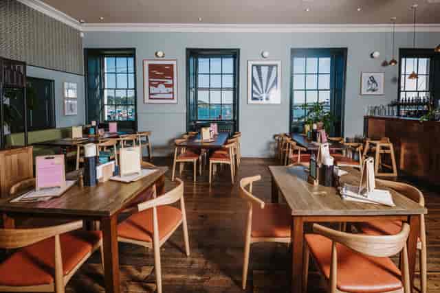 Inviting dining space with wooden tables for small meetings and events at Falmouth Stable.