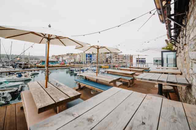 Charming waterfront venue with rustic tables, perfect for outdoor events and gatherings.