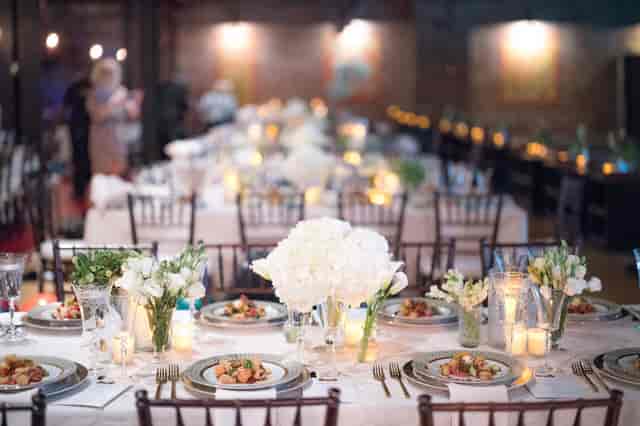 Elegant dining table with white floral centerpieces at Brooklyn Bowl event venue.