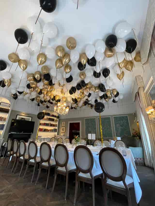 Elegant event space with black, white, and gold balloons for corporate gatherings.