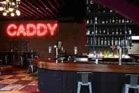 Vibrant Shoreditch bar with neon "CADDY" sign, ideal for networking events and gatherings.