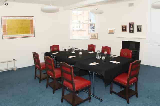 Elegant meeting room with black table and red chairs, perfect for workshops or gatherings.