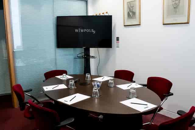 Small meeting room with oval table, notepads, and large screen for professional events.