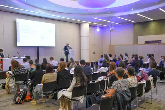 Conference setting with speaker engaging audience in modern AV-equipped room.