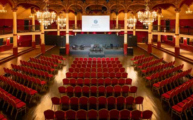 Elegant event space with tiered seating and chandeliers for conferences or galas.