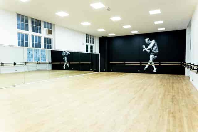 Spacious dance studio with mirrors and wooden flooring for fitness workshops at City Academy.