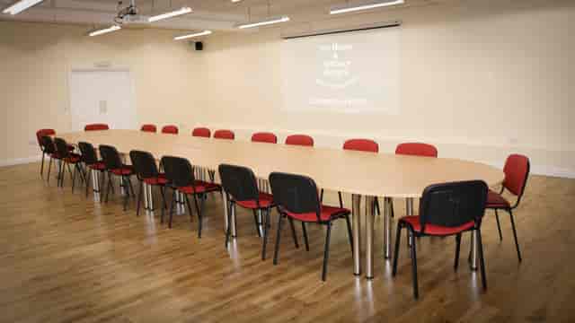 Spacious conference room with oval table, ideal for meetings and presentations.