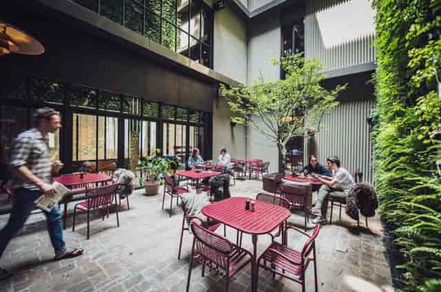 Charming indoor-outdoor space with greenery for casual meetings and networking events.