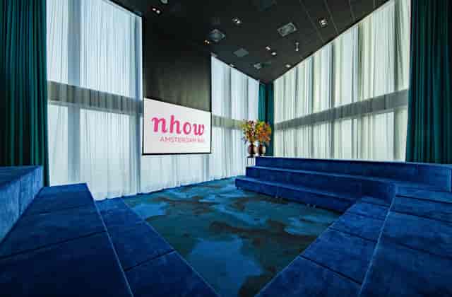 Modern meeting room in NH Hotel Amsterdam with tiered seating for corporate events.