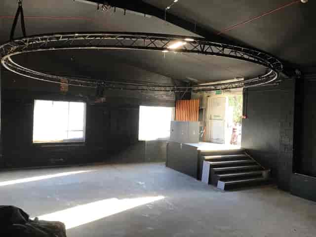 Versatile industrial event space with natural light and circular truss for presentations.