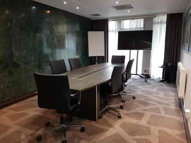 Modern meeting room in Perry Suite, DoubleTree London Ealing, with ergonomic chairs and large screen.