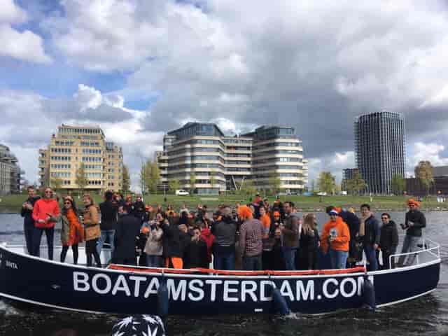 Vibrant group enjoying a corporate boat event in Amsterdam with modern architecture.
