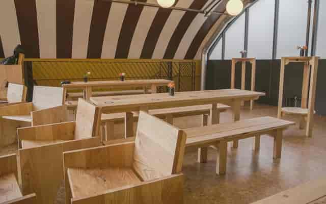 Versatile event space with wooden furniture for meetings and workshops at Locks Industrial Brewery.