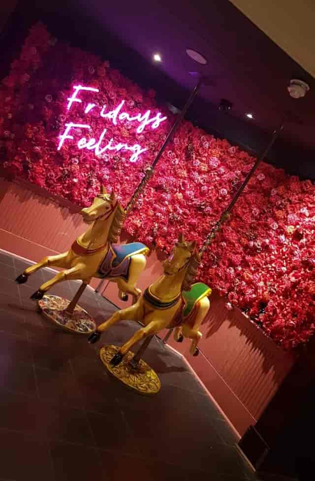Vibrant event space with floral backdrop and carousel horses in Glasgow for themed gatherings.