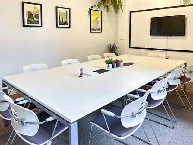 Modern meeting room with large white table, ideal for collaborative sessions.