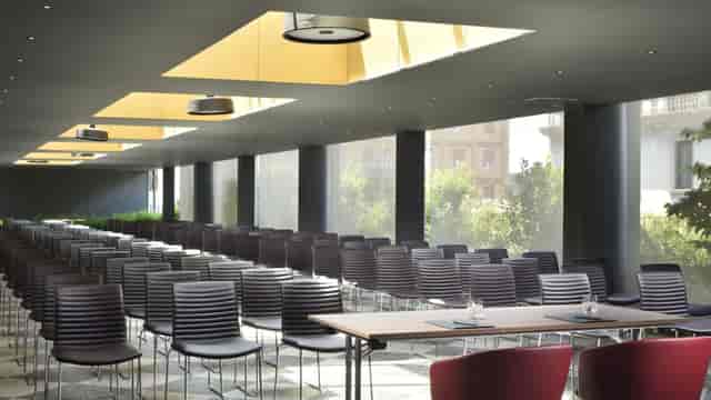 Modern event space with sleek chairs and natural light at Una Hotels Milano Verticale.