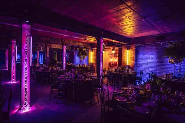 Elegant event space at Tobacco Stores, featuring vibrant uplighting and stylish table settings.